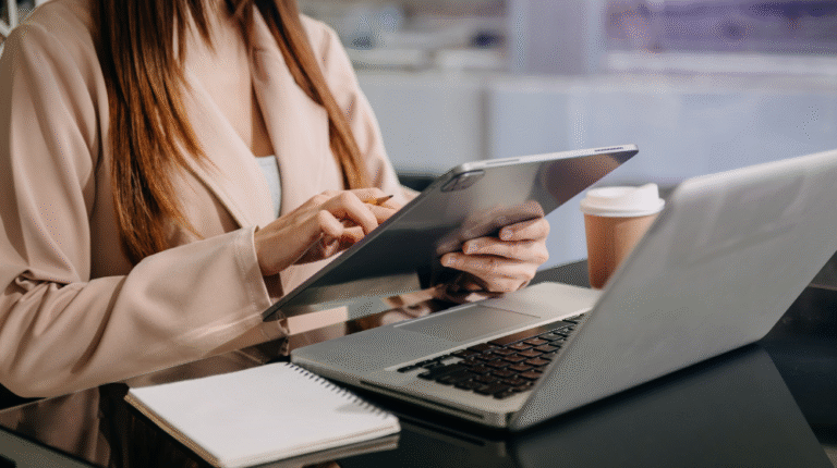 mulher em uma mesa com agenda e notebook, e com um tablet na mão analisando padronização de processos operacionais