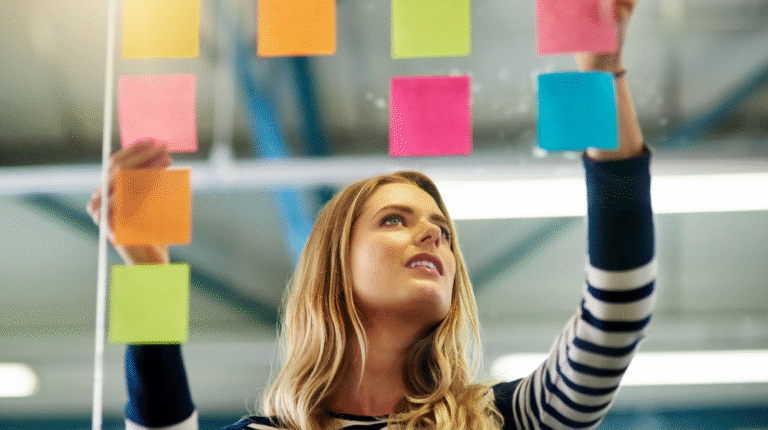 mulher colocando post-it em um painel para fazer plano de ação organizacional